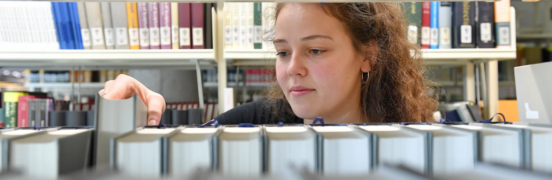 Eine junge Frau sortiert Bücher in ein Regal