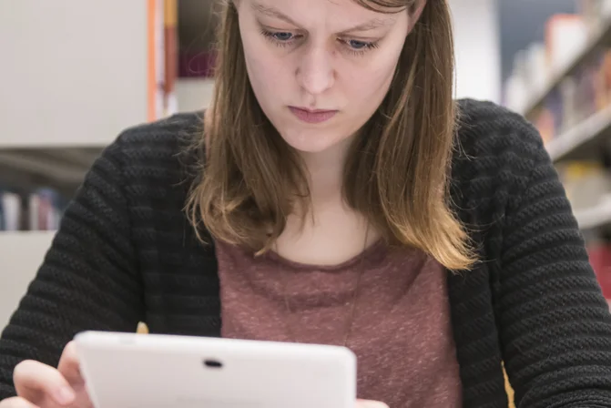 Eine junge Frau arbeitet am Tablet