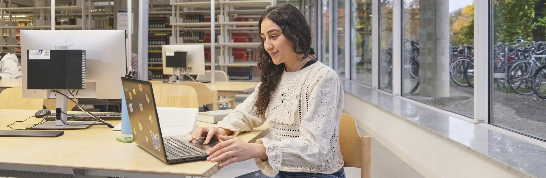 Person arbeitet in der Bibliothek am Laptop